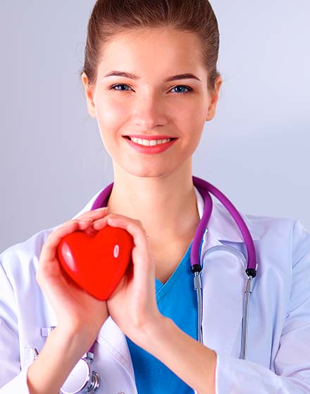 женщина врач улыбается и держит игрушечное сердце в руках